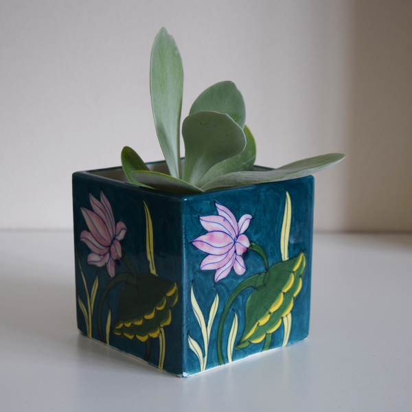 green pot with plant hand-painted in pink, green, and yellow water lilies