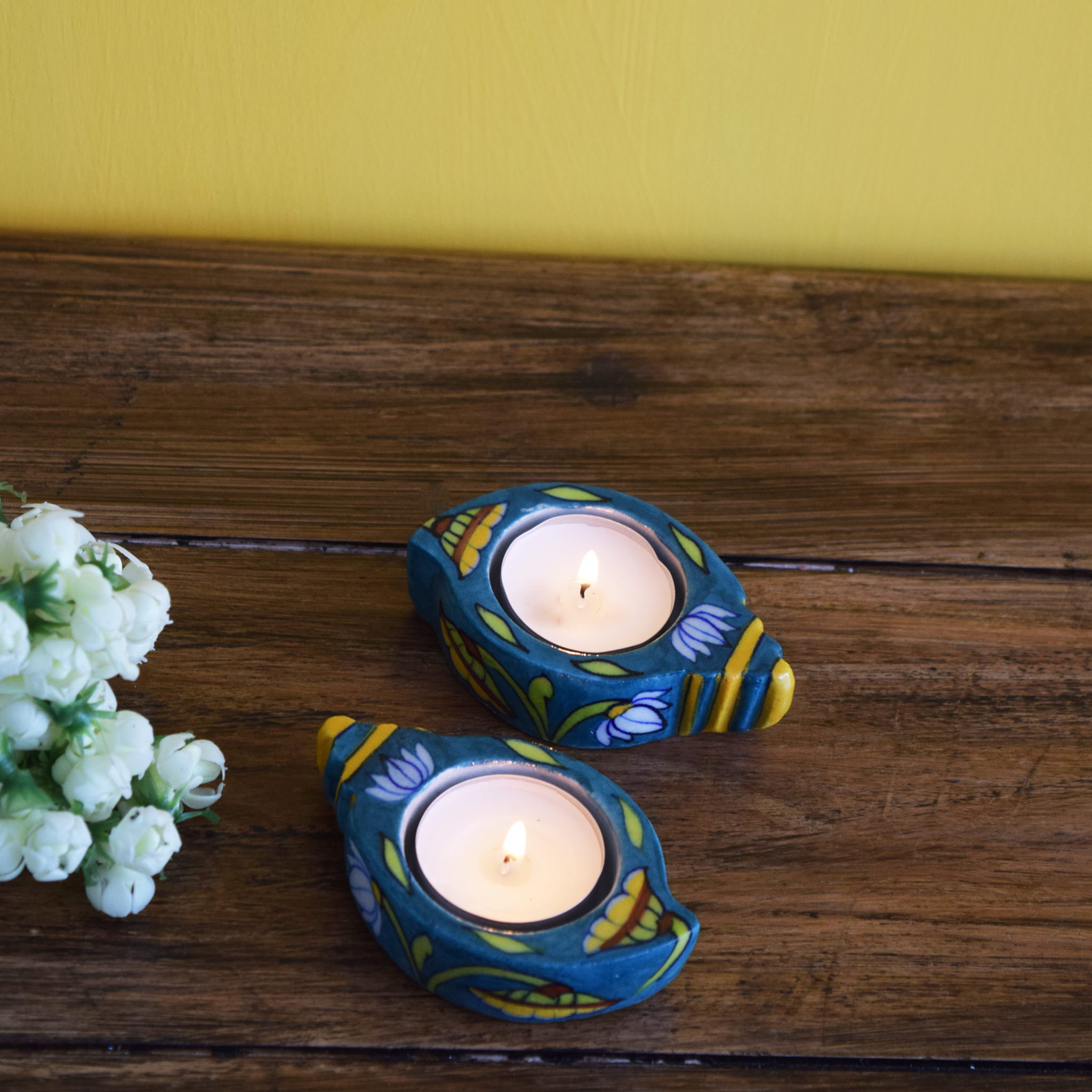  blue conch-shaped tealight holders painted in yellow and brown floral patterns