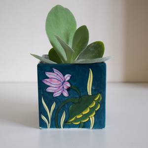 green pot with plant hand-painted in pink, green, and yellow water lilies
