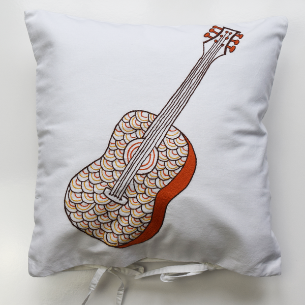 White cushion cover with embroidered guitar pattern