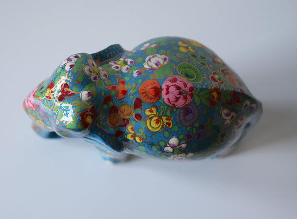 Turquoise paper mache elephant with multicoloured flowers and green leaves on trunk and body- top view