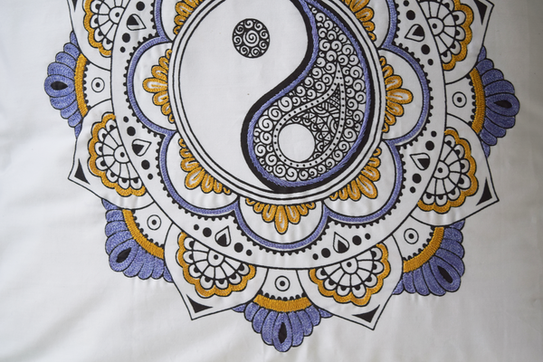 details of embroidery on yin yang cushion cover in shades of ochre/mustard and lilac