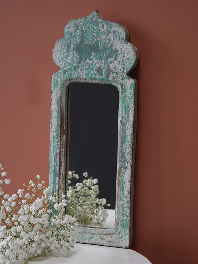 Green blue, distressed mirror against terracotta background
