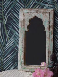 mint green distressed mirror against leafy wallpaper