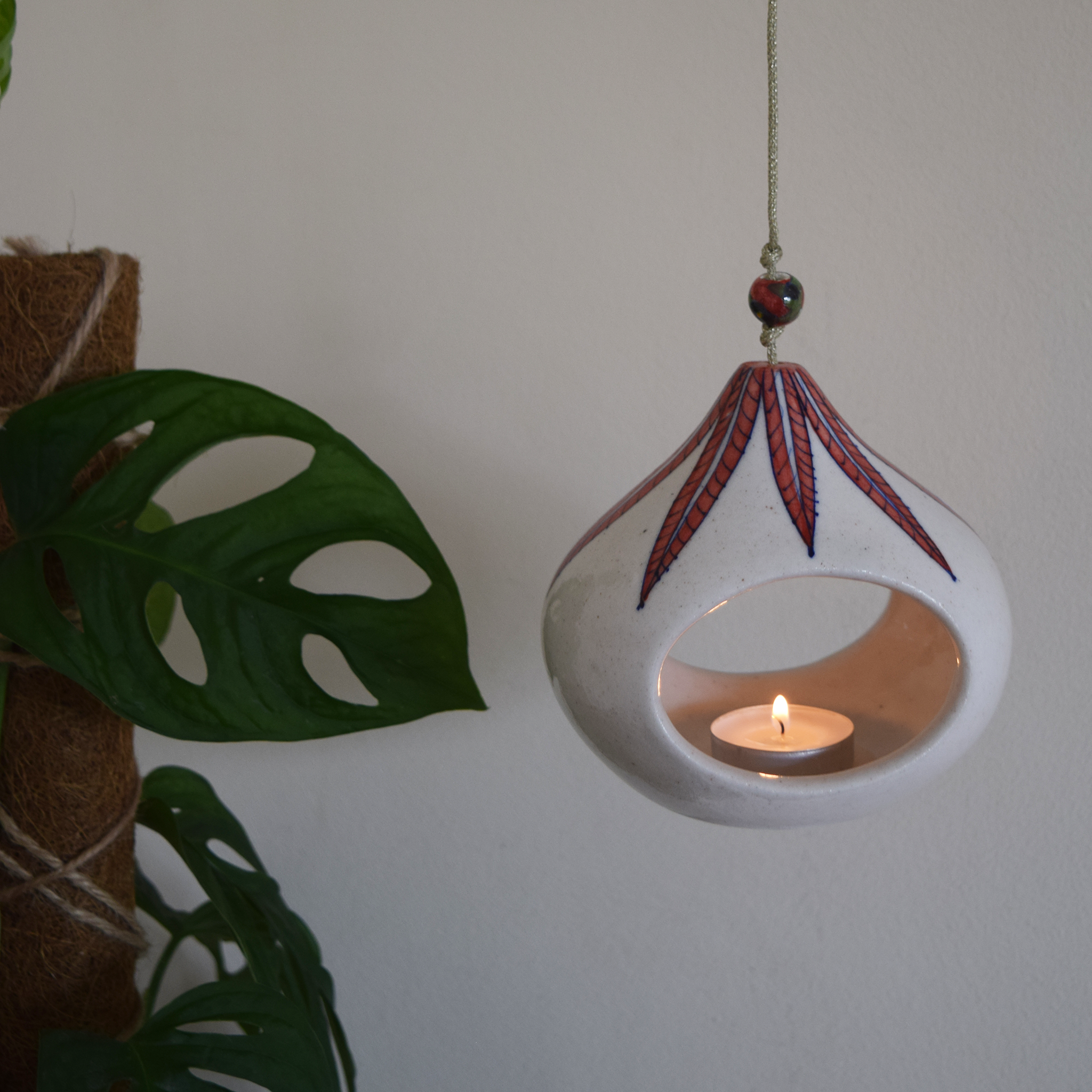 white tea light with red leaf pattern